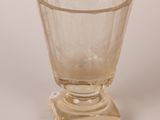 an old fashioned glass cup sitting on top of a glass stand