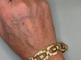 a woman ' s hand that is holding a gold bracelet