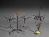 deux sculptures métalliques représentant des fleurs et un bougeoir posés sur une surface grise