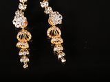 a pair of gold and crystal earrings on a black surface