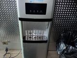 un distributeur d'eau posé par terre à côté d'une poubelle
