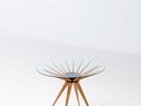 a table with a glass top and wooden legs on a white surface