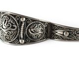 an image of a close up of a silver bracelet on a white surface