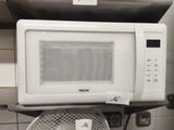 a microwave sitting on top of a fan in a kitchen