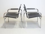 pair of chrome and black chairs with black leather seats in a white room