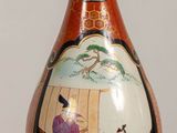 a vase with a painting on it sitting on a table