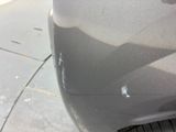 the front of a car with a dent on it ' s bumper