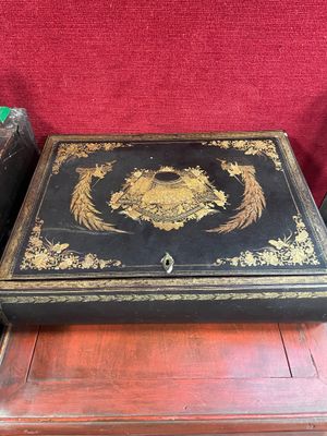 une boîte noire et dorée posée sur une table en bois