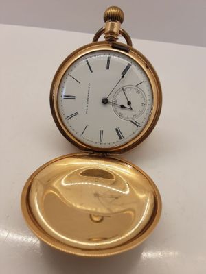 une image représentant une montre de poche en or posée sur une table blanche