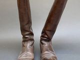 une paire de bottes en cuir marron posées sur une surface grise