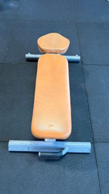an orange bench sitting on the floor in the gym