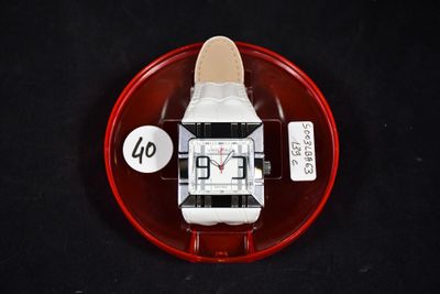 une montre blanche posée sur une assiette rouge, elle-même posée sur une table noire