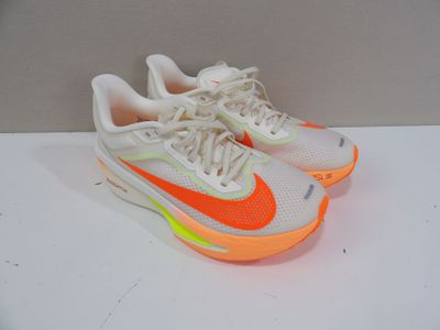 une paire de baskets blanches et orange posées sur une surface blanche