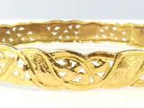 an image of a close up of a gold bracelet on a white surface