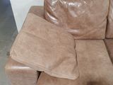 a brown leather couch with pillows on it in a room