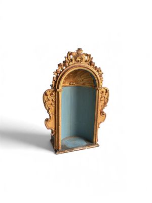 une petite étagère dorée et bleue sur laquelle est posé un miroir