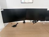two computer monitors sitting on top of a wooden desk