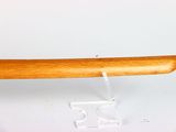 a wooden baseball bat on a stand on a white surface