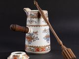 a white pitcher and a wooden spoon on a black background