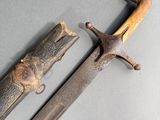 an old sword with a wooden handle on a gray surface