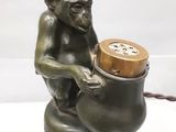 une statue représentant un singe assis sur un pot contenant une horloge