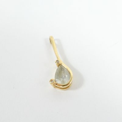 a close up of a gold plated pendant with a green tear shaped stone