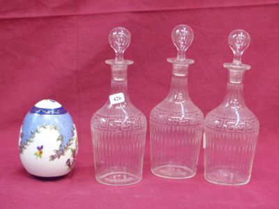 three empty glass bottles sitting next to an egg on a pink background