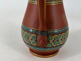 a brown vase with a blue and green design on it