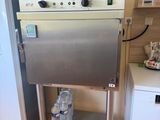 a stainless steel oven sitting on a stand next to a refrigerator