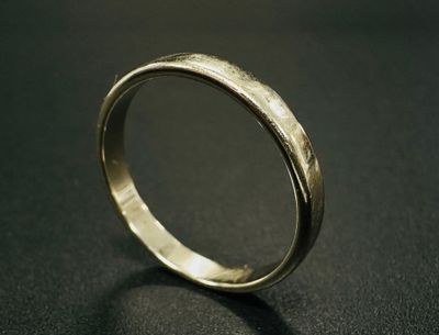 gros plan d'une bague en or sur une surface noire