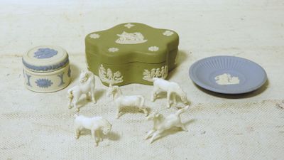 une boîte verte avec des chevaux blancs et une assiette sur laquelle est posée une assiette bleue
