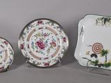 three pieces of china with flowers and leaves are displayed on a table