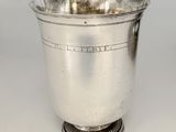 une coupe à vin ancienne en métal plaqué argent, posée sur un socle en métal