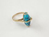 gros plan d'une bague en or avec une pierre turquoise