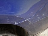 a close up of a blue car with a denting on it