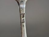 a silver spoon with a bird on it sitting on top of a table