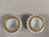 two white and gold vases on a table with a white background