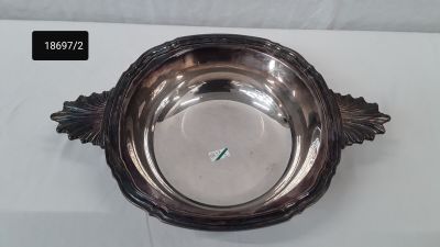 un bol en argent posé sur une table recouverte d'une nappe blanche
