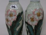 two vases with flowers painted on them sitting on a table