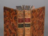 an old book opened to show two books on a gray surface