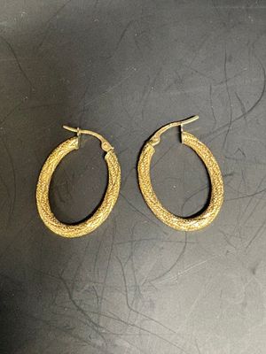 pair of gold toned hoop earrings on a black surface