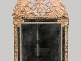 un miroir richement sculpté, doté d'un cadre doré sur fond gris