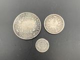 three silver coins sitting next to each other on a black surface