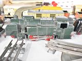 a green train on the tracks next to other toy trains