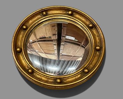 a gold porthole mirror on the wall of a building