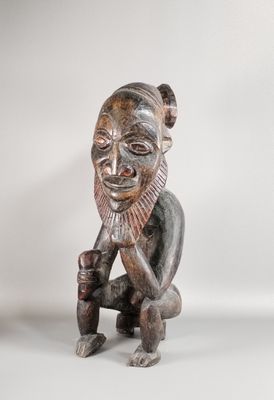 a wooden statue of a man with a beard sitting on his knees