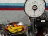 un bol de fruits posé sur une table, à côté d'une balance