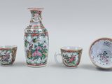 three cups and a vase sitting next to each other