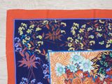 an orange and blue scarf with a picture of flowers on it