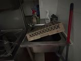 a metal sink in a small kitchen with a mop next to it